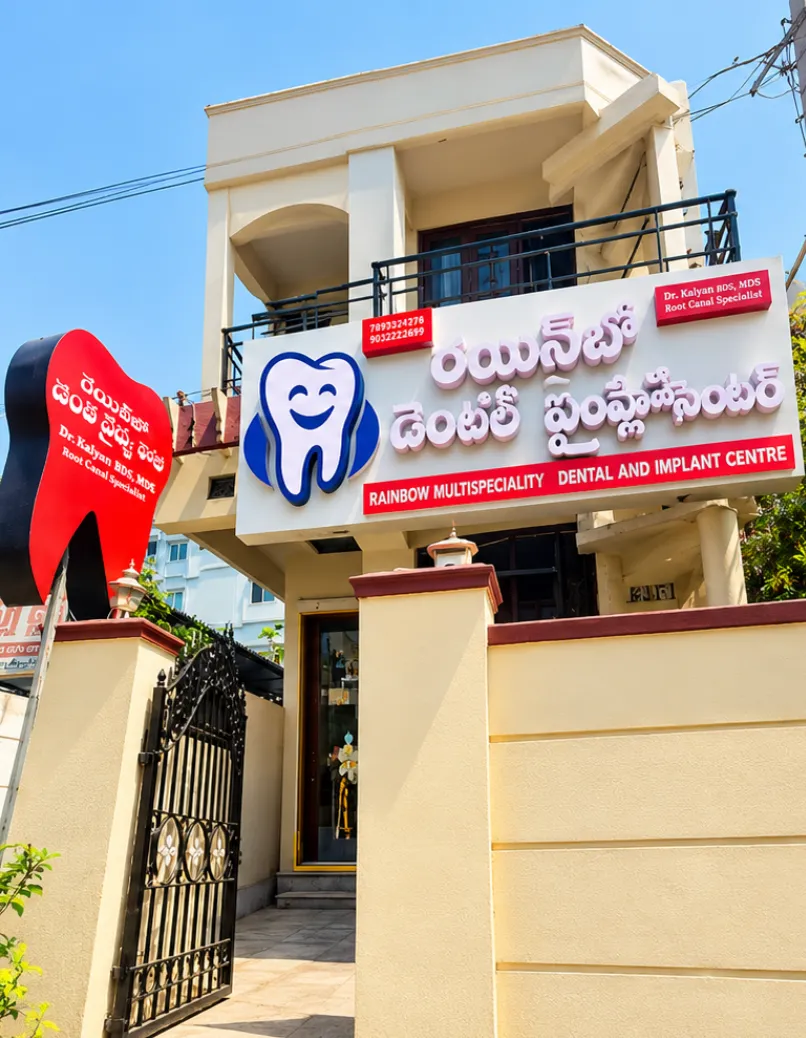 The Jagannaickpur clinic building with its signboards and the tooth-shaped sign at the gate at Rainbow Dental Multispeciality Clinic, Kakinada.